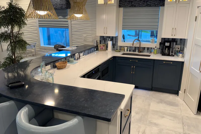 Slide: The Image of Modern kitchen with blue and white cabinetry, marble countertops, and stylish pendant lighting. - 44