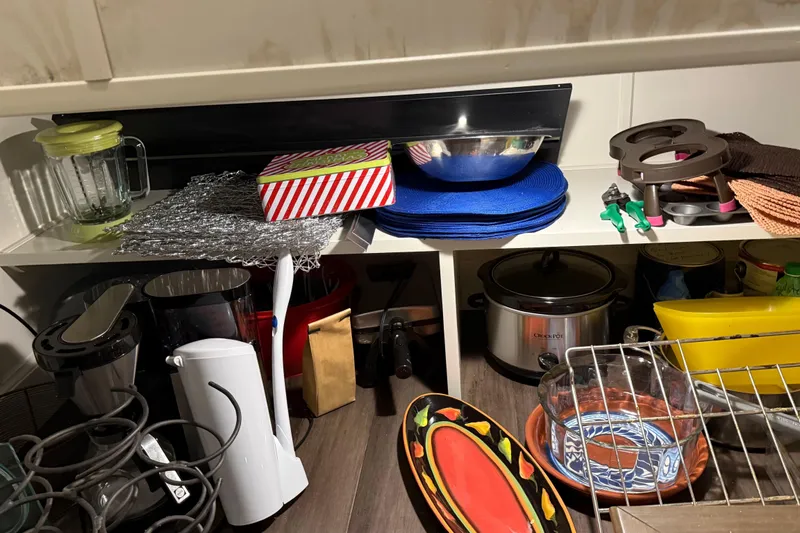 Slide: The Image of Kitchen counter with various appliances, dishes, and utensils, including a blender and slow cooker. - 49