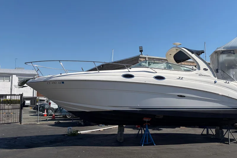 The Image of 2004 Sea Ray Sundancer 280 boat on stands in a marina under clear blue sky. - 0