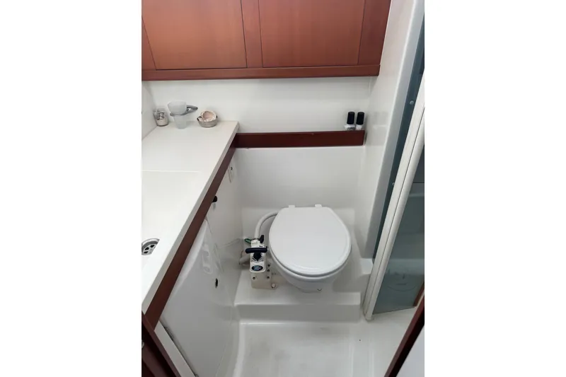Slide: The Image of Bathroom interior of 2007 Beneteau Oceanis 49 yacht, featuring compact toilet and wooden cabinetry. - 12