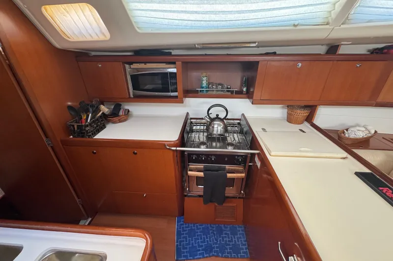 Slide: The Image of Galley kitchen in 2007 Beneteau Oceanis 49 yacht with stove, microwave, and wooden cabinetry. - 20
