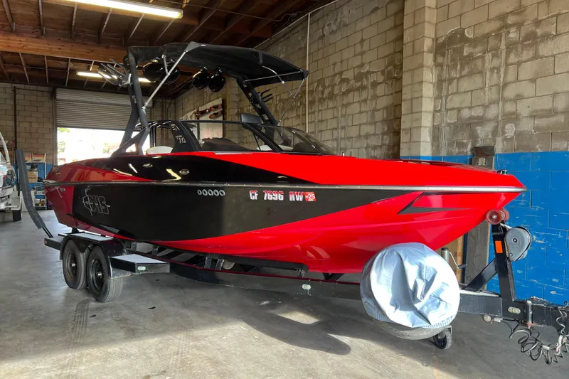 The Image of 2016 Axis T22 boat in red and black, parked indoors on a trailer. - 0