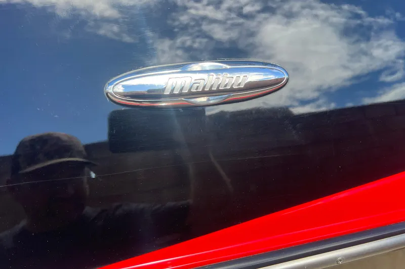 Slide: The Image of 2016 Axis T22 boat with Malibu emblem, reflecting blue sky and clouds. - 14