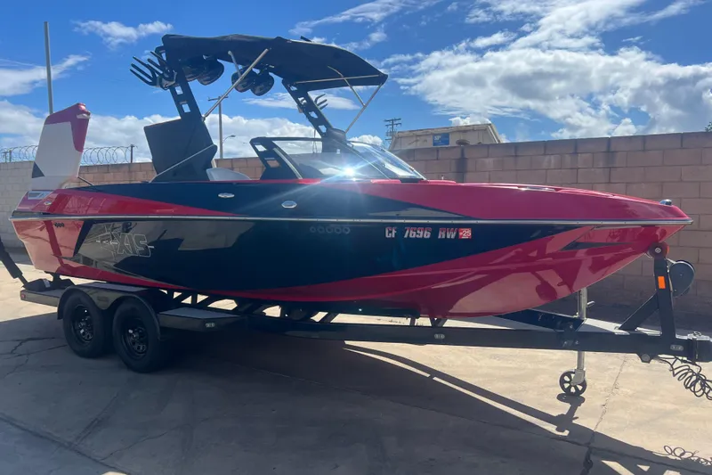 Slide: The Image of 2016 Axis T22 boat on trailer, vibrant red and black design, parked outdoors under blue sky. - 40