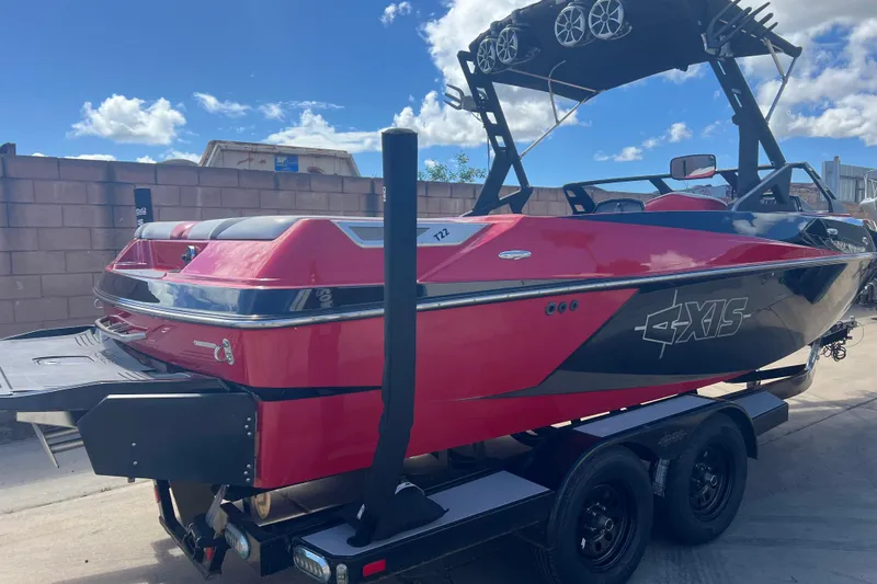 Slide: The Image of 2016 Axis T22 boat in vibrant red and black, parked on a trailer under a blue sky. - 5