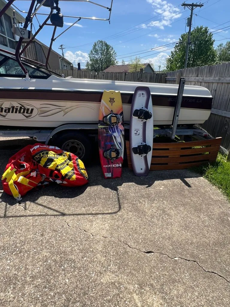 Slide: The Image of 1997 Malibu Sunsetter LX boat with wakeboards and tube outdoors. - 8