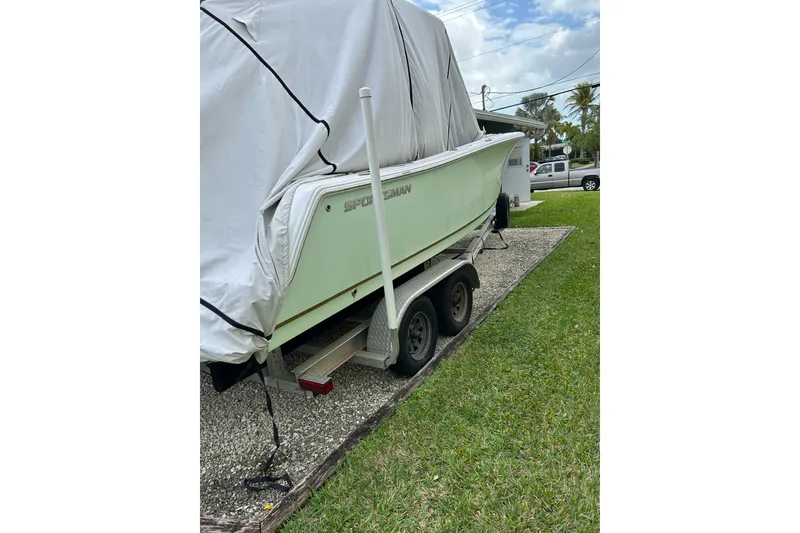 Slide: The Image of 2018 Sportsman Heritage 231 Center Console boat covered on a trailer in a driveway. - 4