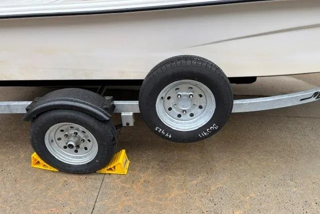 Slide: The Image of Trailer wheels of a 2025 Mako Pro Skiff 13 CC, secured with yellow chocks. - 13