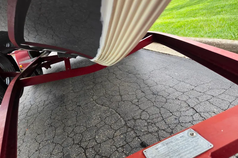 Slide: The Image of Red trailer frame under a Ranger R72 Sport boat, parked on cracked asphalt. - 7