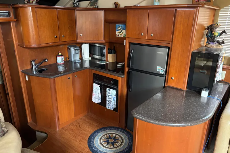 Slide: The Image of 2007 Silverton 43 Motor Yacht kitchen with wood cabinets, black countertops, and modern appliances. - 17