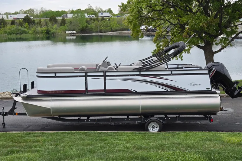 The Image of 2024 Qwest Angler Qwest XRE pontoon boat on trailer by a scenic lake. - 0