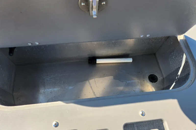 Slide: The Image of Storage compartment of 2024 Qwest Angler Qwest XRE boat, featuring a drain and latch. - 17
