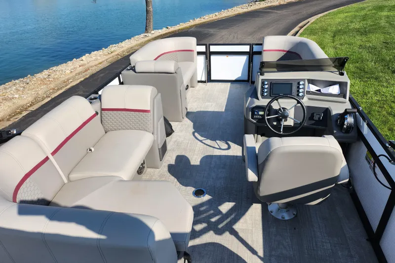 Slide: The Image of 2024 Qwest Angler Qwest XRE pontoon boat interior with seating and steering console by the water. - 19
