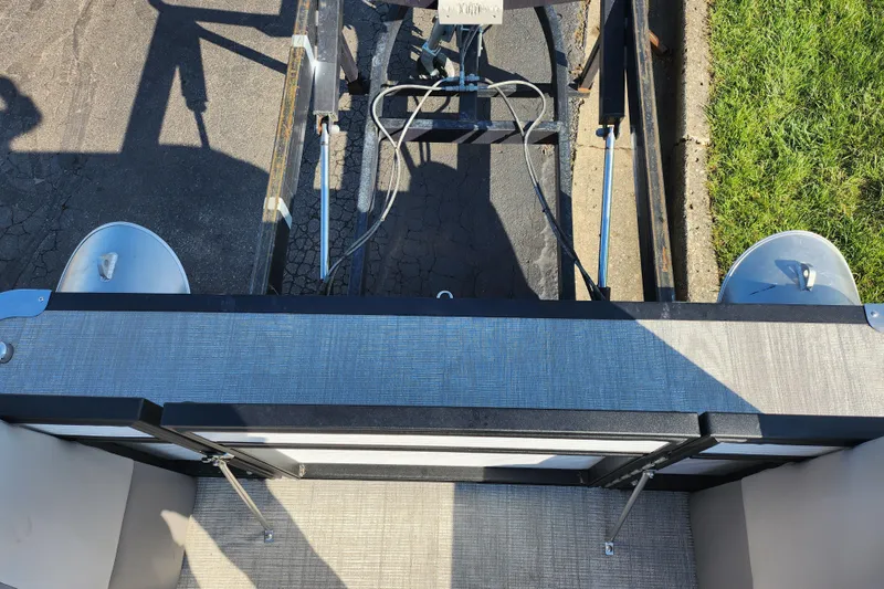 Slide: The Image of 2024 Qwest Angler Qwest XRE pontoon boat trailer view with metal frame and grass. - 23