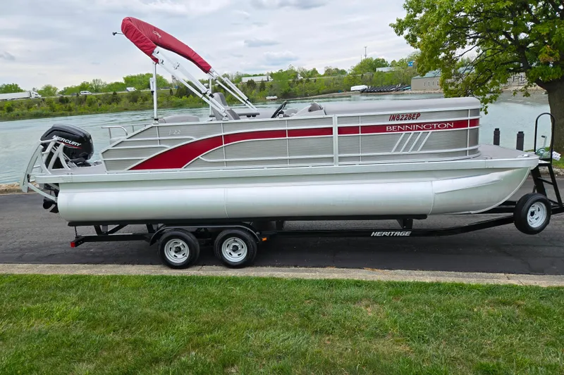 Slide: The Image of 2023 Bennington 22 LSB pontoon boat on trailer by a riverbank. - 10