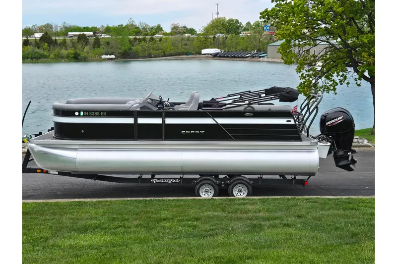 The Image of 2022 Crest Classic DLX 220 pontoon boat on trailer by a scenic lake. - 0
