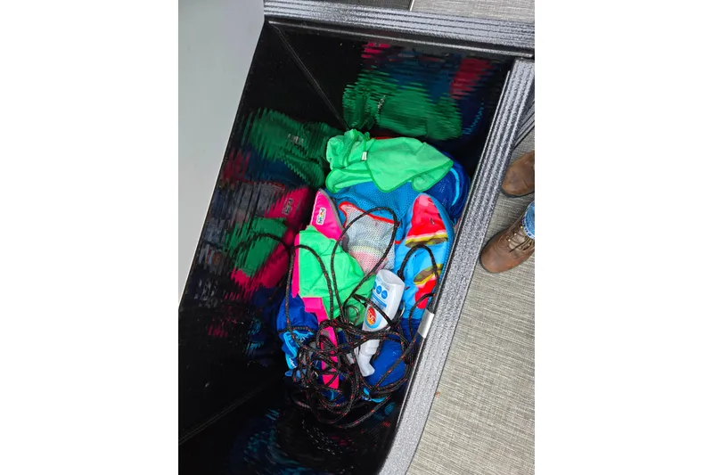 Slide: The Image of Storage compartment in 2022 Crest Classic DLX 220 boat with colorful gear and ropes. - 17
