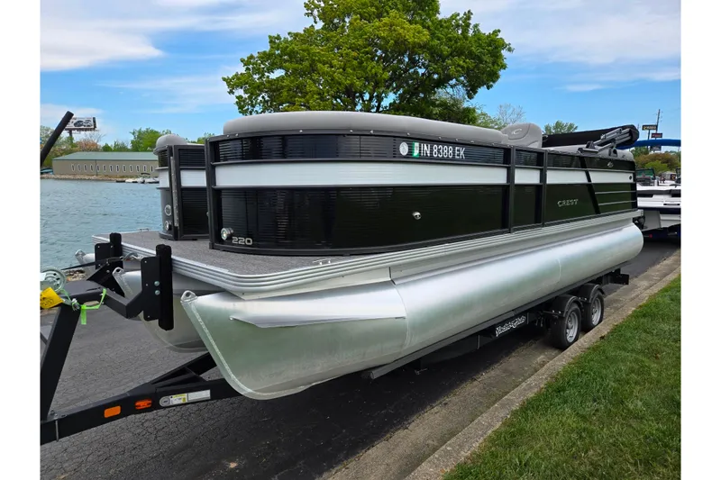 Slide: The Image of 2022 Crest Classic DLX 220 pontoon boat on trailer by a lakeside. - 7