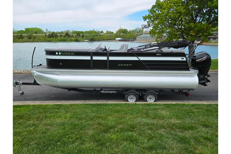 Slide: The Image of 2022 Crest Classic DLX 220 pontoon boat on trailer by a lake. - 8