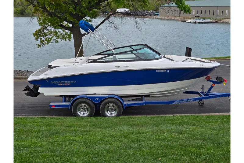 The Image of 2020 Monterey M-20 boat on trailer by a lakeside, featuring sleek blue and white design. - 0