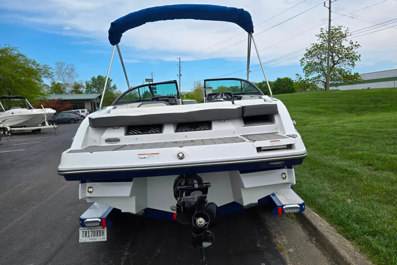 Slide: The Image of 2020 Monterey M-20 boat with blue canopy, parked on pavement near grass. - 2