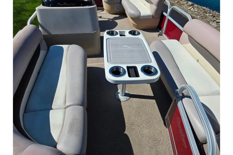 Slide: The Image of 2014 Sun Tracker Party Barge 20 DLX interior with seating and table, near water. - 13