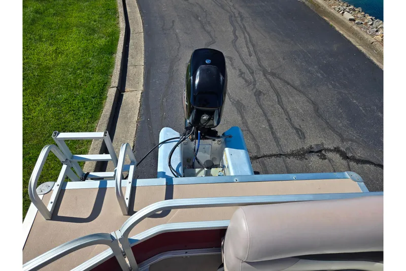Slide: The Image of 2014 Sun Tracker Party Barge 20 DLX with outboard motor, docked near a paved path. - 19