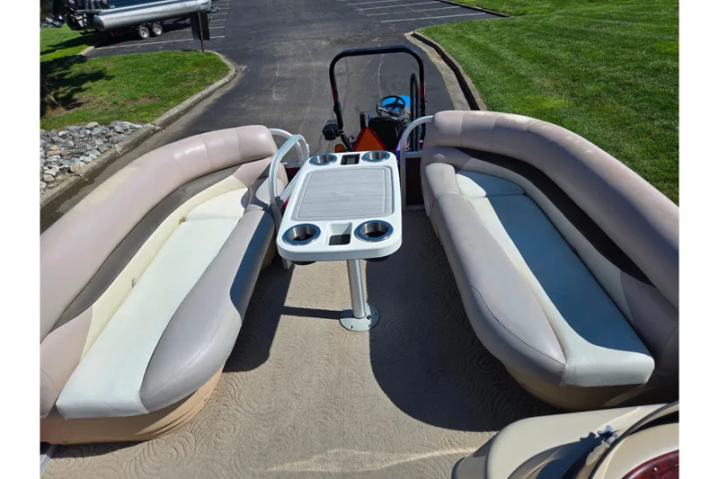 Slide: The Image of 2014 Sun Tracker Party Barge 20 DLX interior with seating and table, parked on pavement. - 25