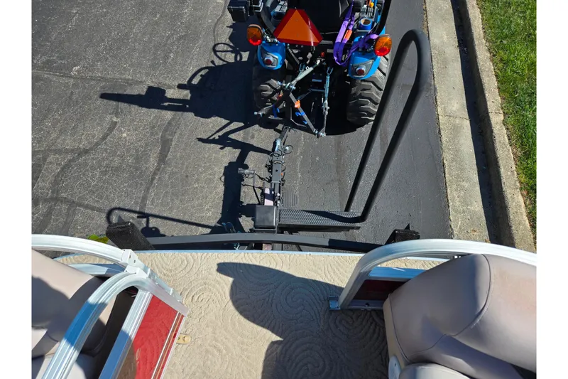 Slide: The Image of 2014 Sun Tracker Party Barge 20 DLX hitched to a blue tractor on pavement. - 26