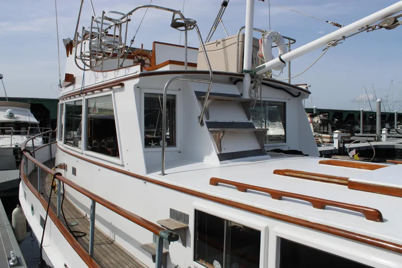 Slide: The Image of 1971 Grand Banks 36 Classic yacht docked, showcasing wooden railings and upper deck details. - 9