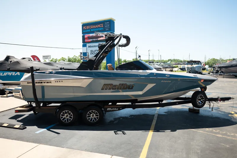 Slide: The Image of 2022 Malibu Wakesetter 23 MXZ boat on trailer at dealership, sunny day. - 8