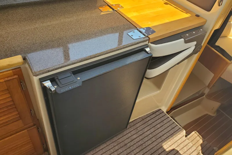 Slide: The Image of 2013 Cutwater 26 interior with Nova Kool fridge and wooden cabinetry. - 12