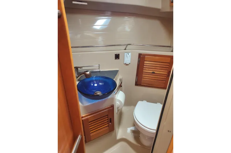 Slide: The Image of 2013 Cutwater 26 boat bathroom with blue sink, toilet, and wooden cabinets. - 14