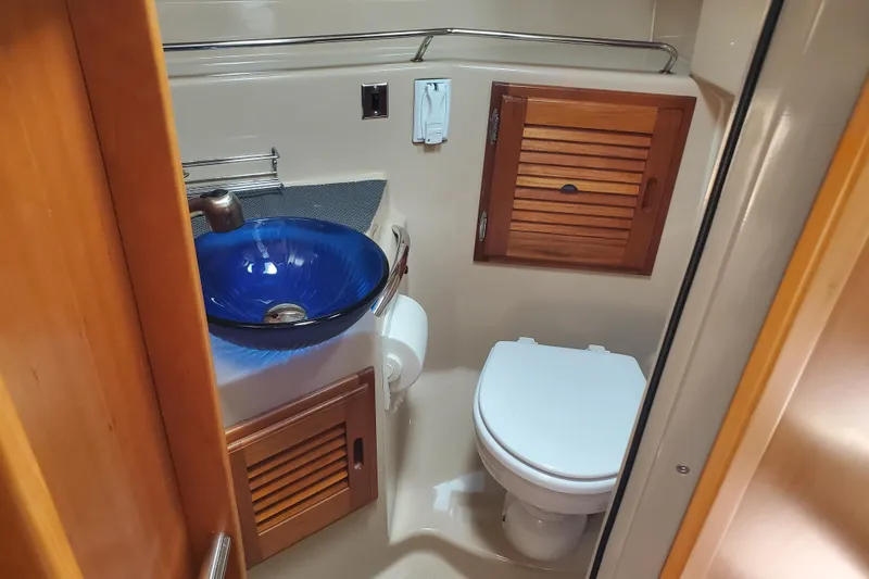 Slide: The Image of 2013 Cutwater 26 boat bathroom with blue glass sink and wooden cabinetry. - 15