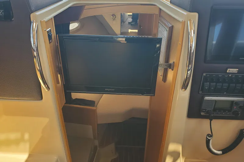 Slide: The Image of Interior of a 2013 Cutwater 26 boat featuring a mounted TV and control panel. - 16