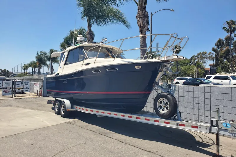 Slide: The Image of 2013 Cutwater 26 boat on trailer, parked outdoors under clear blue sky. - 2