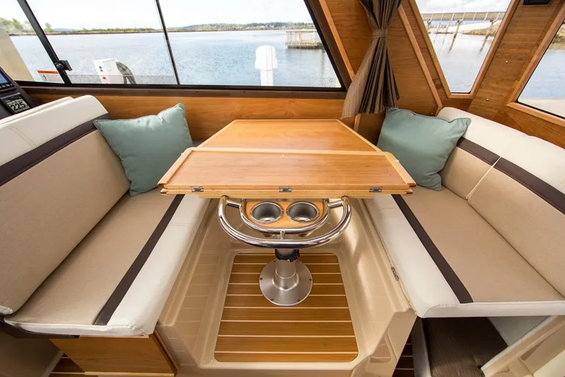 Slide: The Image of Manufacturer Provided Image: Interior of a 2016 Cutwater 26 boat with a wooden table and cushioned seating. - 43
