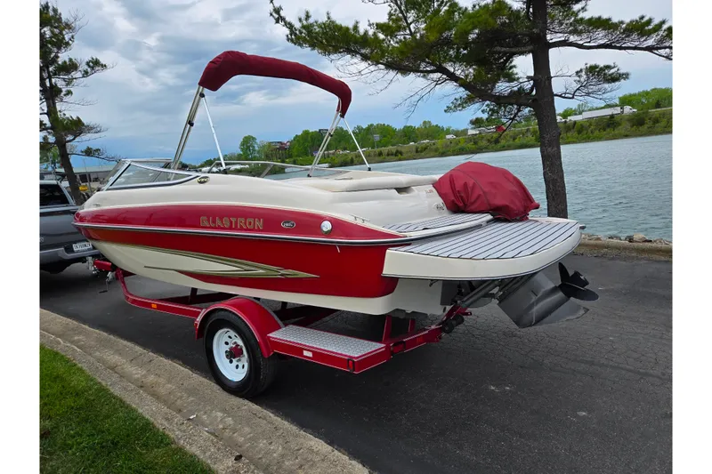 Slide: The Image of 2005 Glastron GX 205 boat on trailer by a lakeside road. - 1