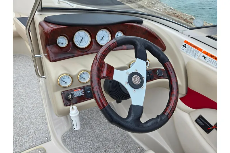 Slide: The Image of Steering wheel and dashboard of 2005 Glastron GX 205 boat, featuring gauges and controls. - 13