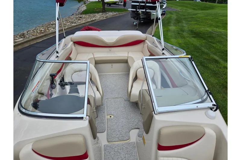 Slide: The Image of 2005 Glastron GX 205 boat interior with beige and red seating, near a lake. - 18