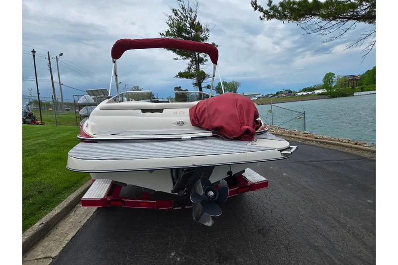 Slide: The Image of 2005 Glastron GX 205 boat on trailer by a lakeside, overcast sky. - 2