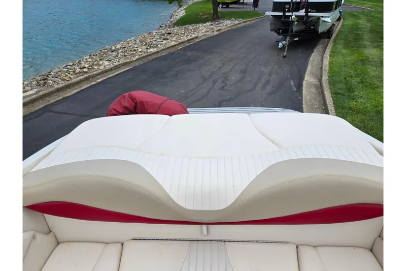 Slide: The Image of 2005 Glastron GX 205 boat interior with white and red seating near a lakeside. - 21