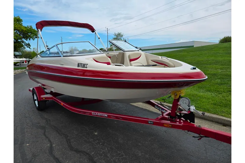 Slide: The Image of 2005 Glastron GX 205 boat with red accents on a matching trailer, parked outdoors. - 5