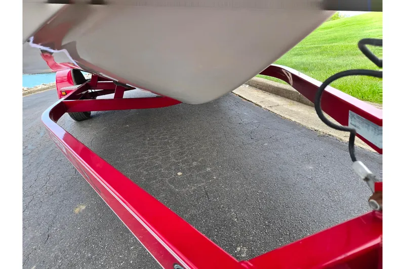 Slide: The Image of Red trailer holding a 2005 Glastron GX 205 boat on a paved road. - 7