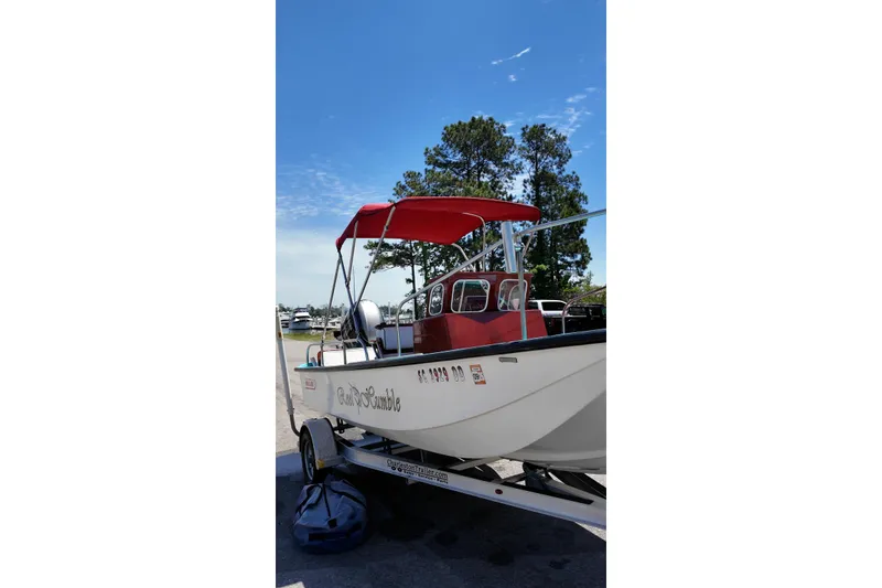 The Image of 1969 Boston Whaler 17 Montauk boat with red canopy on trailer, clear sky background. - 1