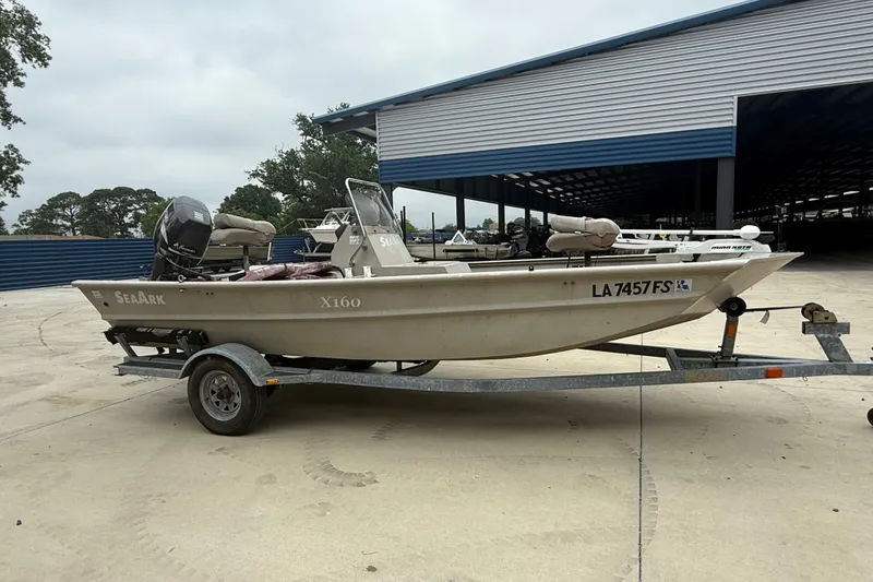 Slide: The Image of 2008 SeaArk 1652 MV boat on trailer, parked outdoors near a storage facility. - 1