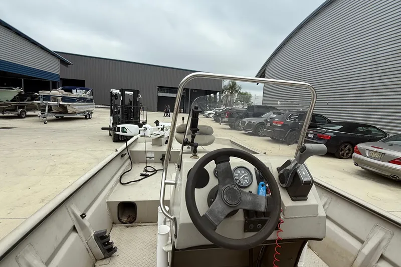 Slide: The Image of 2008 SeaArk 1652 MV boat interior with steering wheel, parked near warehouse and vehicles. - 10