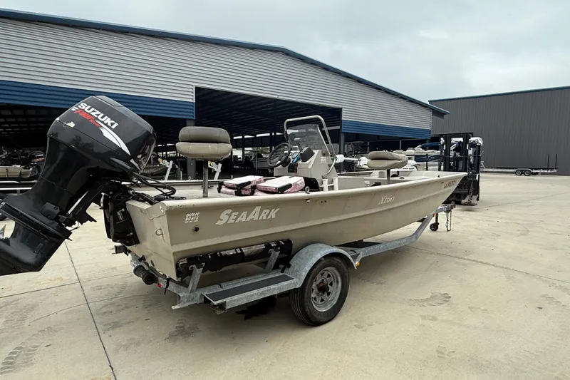 Slide: The Image of 2008 SeaArk 1652 MV boat on trailer with Suzuki outboard motor, parked outdoors. - 2