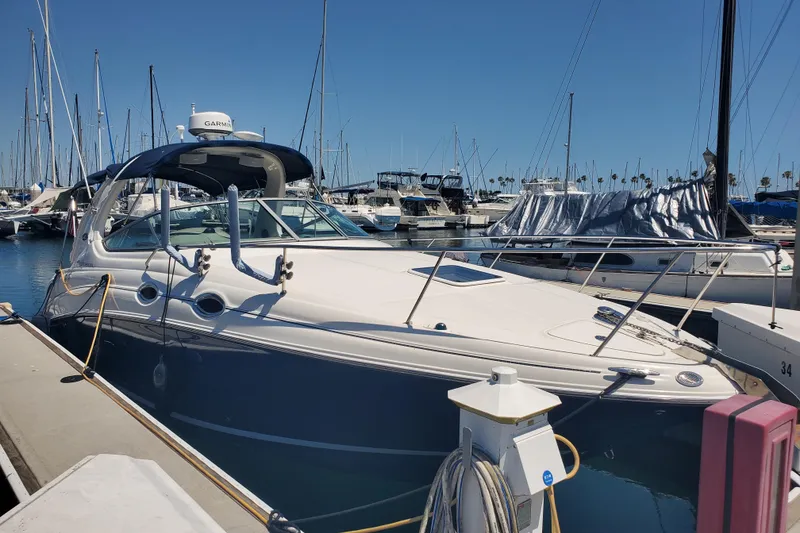 The Image of 2008 Sea Ray Sundancer 280 docked at marina, surrounded by sailboats under clear blue sky. - 0