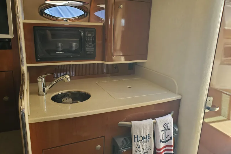 Slide: The Image of 2008 Sea Ray Sundancer 280 interior kitchenette with sink, microwave, and nautical-themed towel. - 16